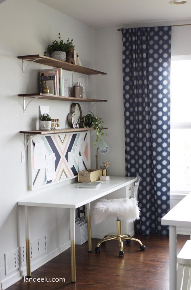 a white desk sitting in front of a window next to a wall mounted book shelf