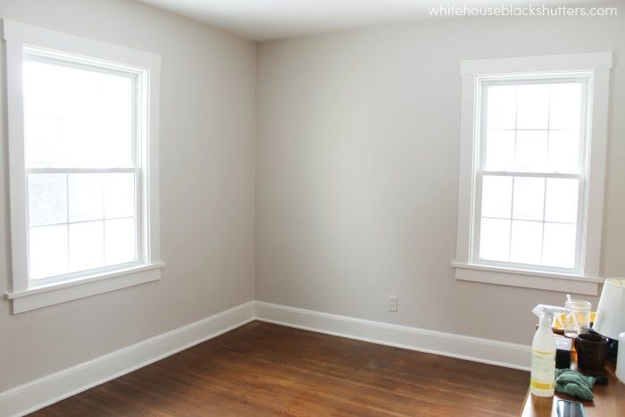 an empty room with two windows and hard wood flooring on the other side of the room