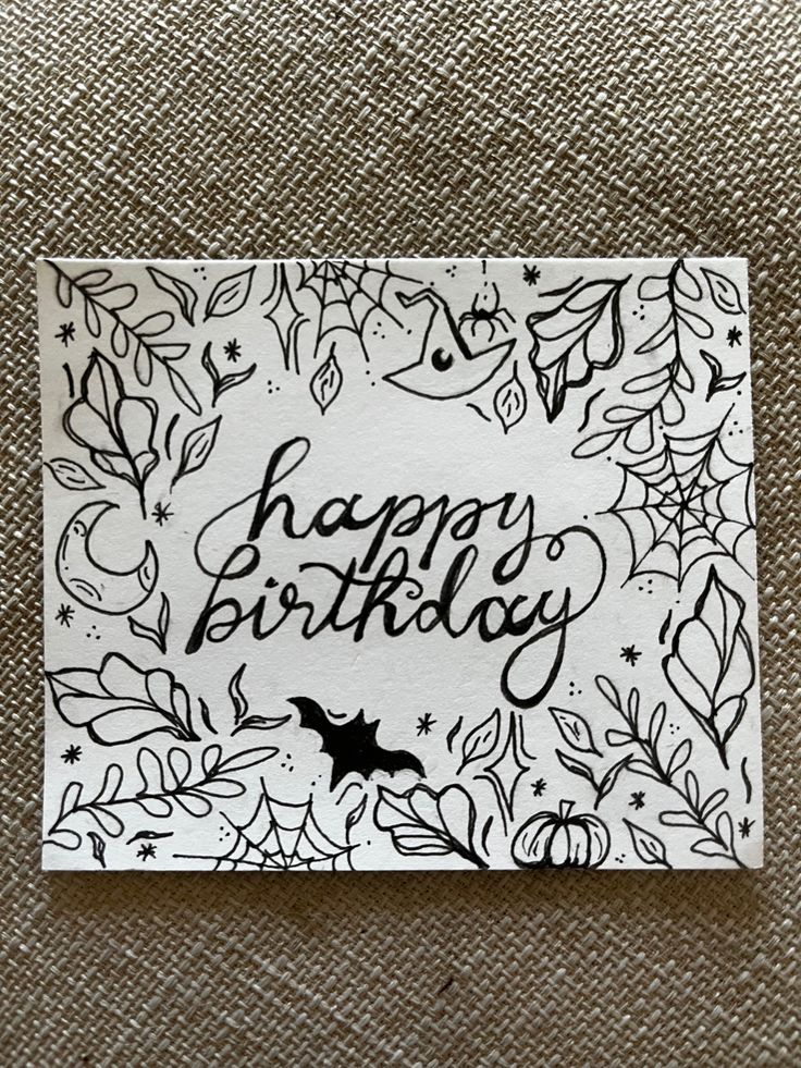 a birthday card with the words happy birthday written in black ink on white paper surrounded by leaves and bats