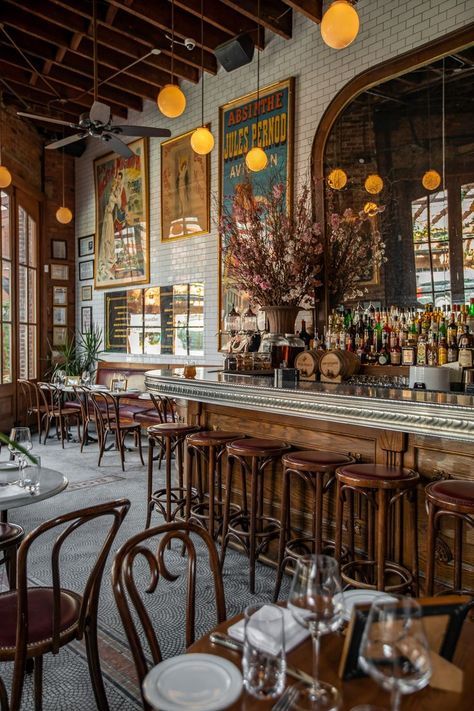 an empty restaurant with many tables and chairs in front of the bar, along with posters on the wall