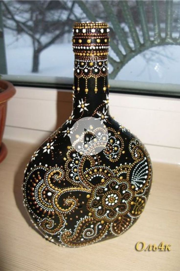 a black and gold vase sitting on top of a wooden table next to a window