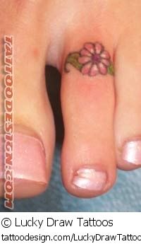 a small flower tattoo on the foot of a woman's left foot with pink nail polish