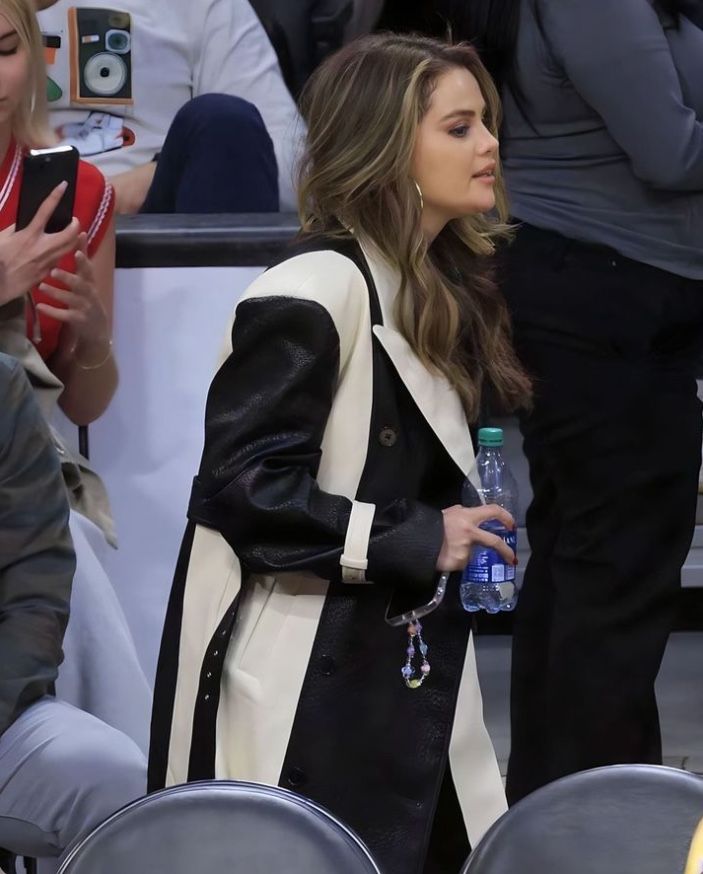 a woman in black and white jacket sitting next to a man with a bottle of water