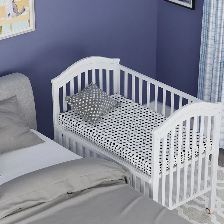 a baby crib in the corner of a room with blue walls and white furniture