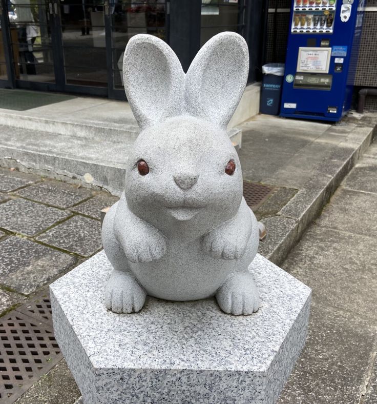 a white rabbit statue sitting on top of a cement block