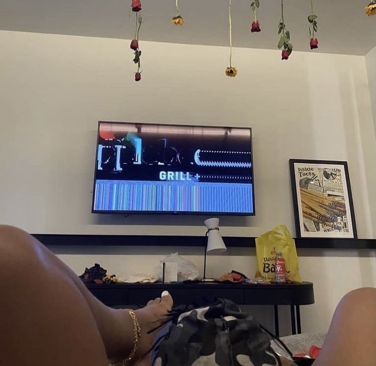 a person laying on the floor in front of a tv with their feet propped up