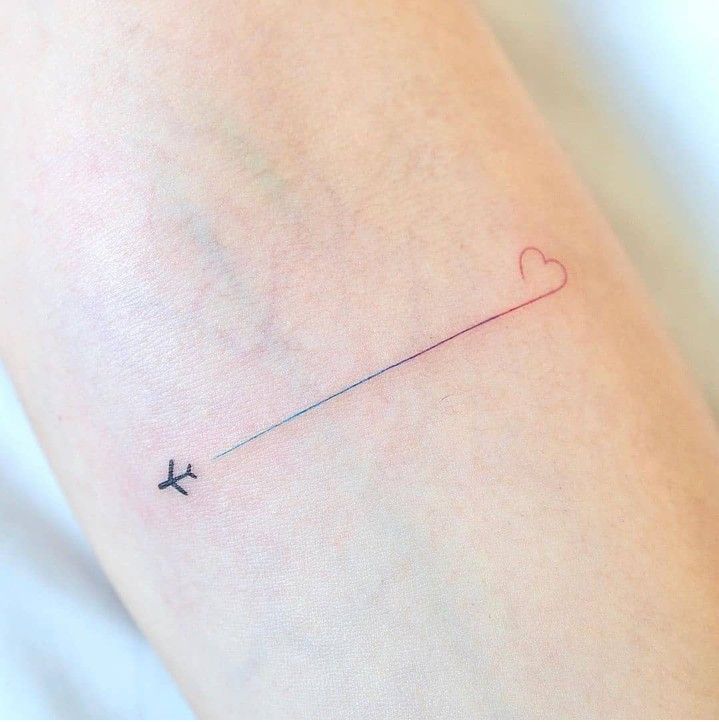 an airplane is flying in the sky with a heart tattoo on it's arm