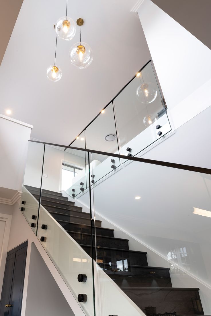 a staircase with glass railing and hanging lights