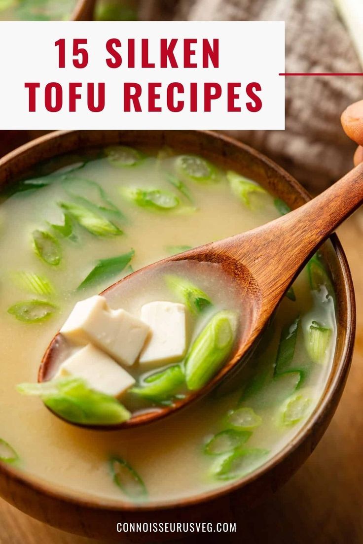 a wooden spoon filled with soup on top of a table