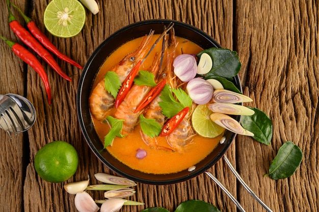 a bowl filled with shrimp and vegetables on top of a wooden table next to limes