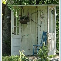 an outhouse in the woods with a blue chair and potted plant on it