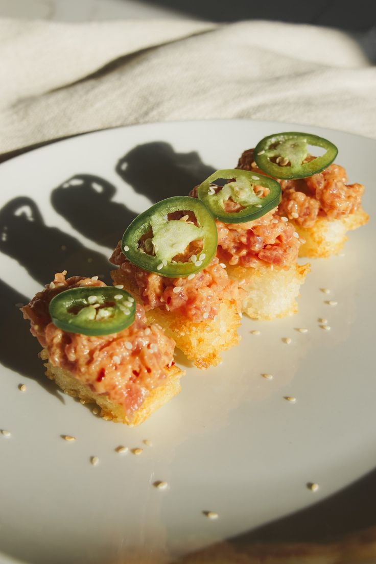 a white plate topped with slices of pizza covered in cheese and jalapenos