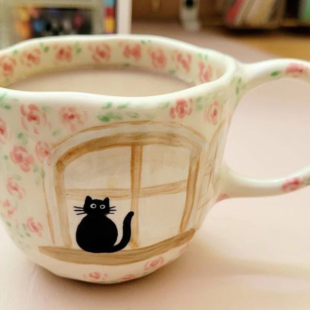 a coffee cup with a black cat painted on it