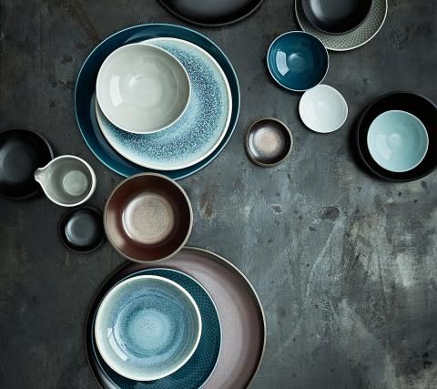 an assortment of plates and bowls on a gray table top, with one empty plate in the middle