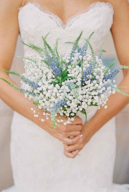 a woman in a wedding dress holding a bouquet of baby's breathflowers