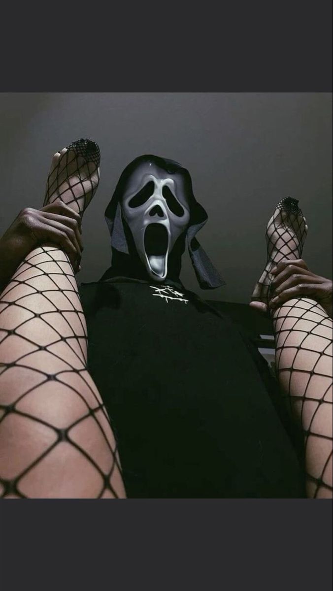 a person wearing a mask and fishnet stockings with their feet up in the air