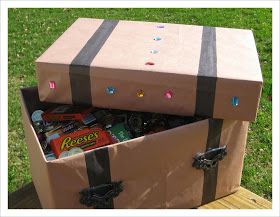 two suitcases with candy in them sitting on a wooden table outside, one opened and the other closed