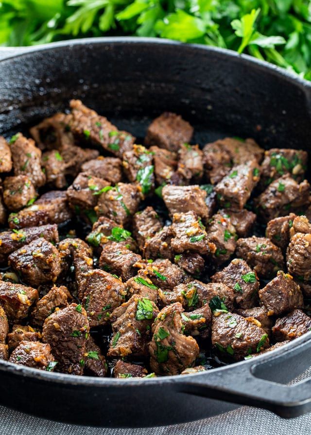 a skillet filled with meat and garnished with parsley on the side