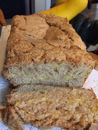 a loaf of banana bread sitting on top of a paper towel next to a banana