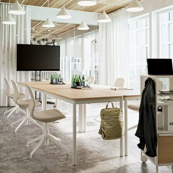 a room with a table, chairs and a laptop on the desk in front of a flat screen tv