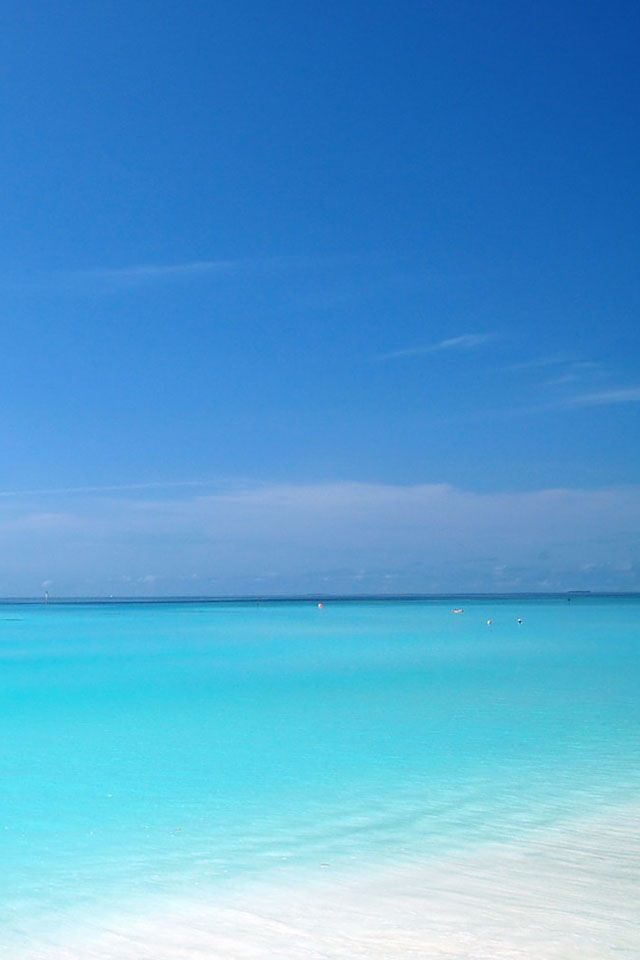 an empty beach with clear blue water and white sand on the bottom right hand side