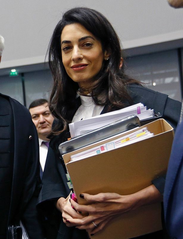 a woman in a suit and tie is holding folders while other people are looking on