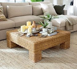 a living room filled with lots of furniture next to a large green plant on top of a coffee table