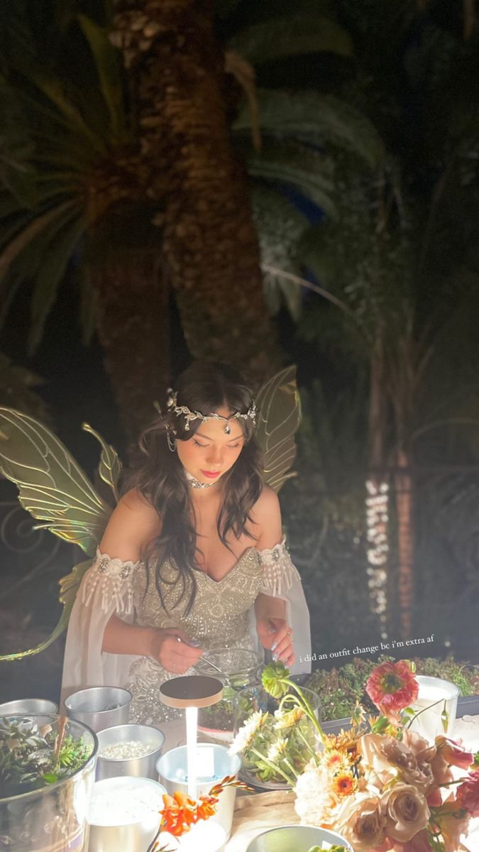 a woman dressed as a fairy preparing food at a table with plates and bowls on it