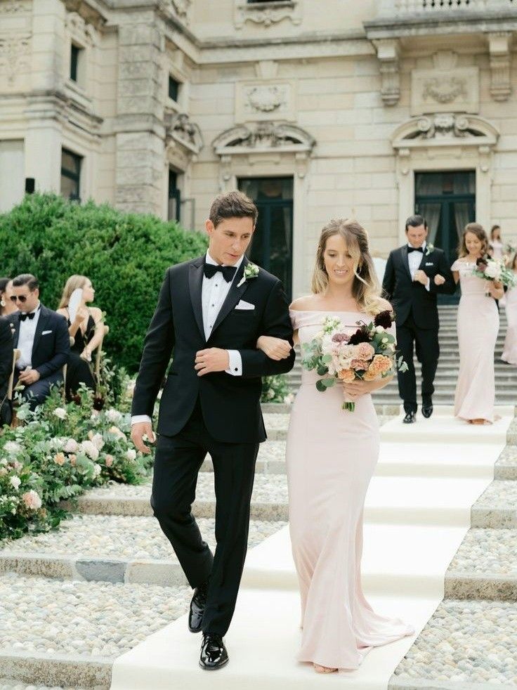 the bride and groom are walking down the stairs at their wedding ceremony in front of an elegant building