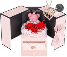 a pink box with red roses and two teddy bears in it next to a necklace