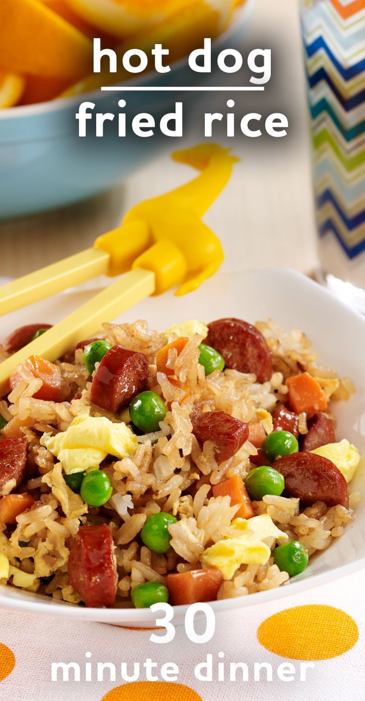 a bowl filled with rice, peas and sausage next to oranges on a table