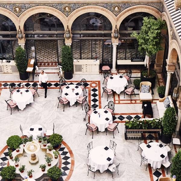 an aerial view of a restaurant with tables and chairs in the center, surrounded by arches