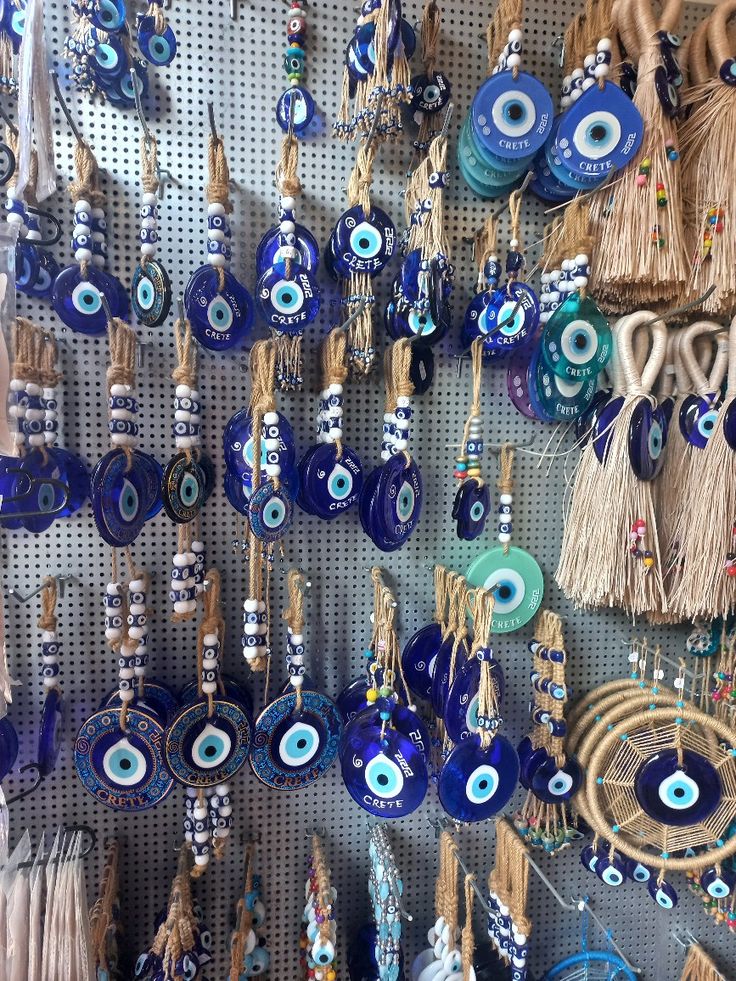 there are many blue and white evil eyes hanging on the wall with tassels