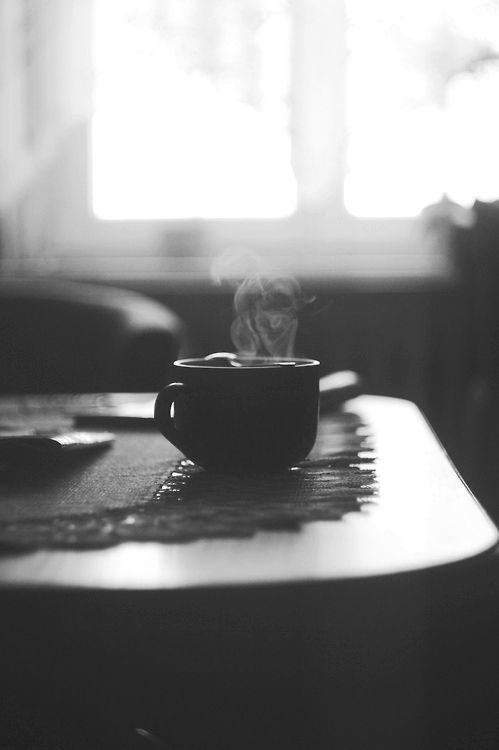 a coffee cup sitting on top of a wooden table next to a window with the words, designed by amirid sadf