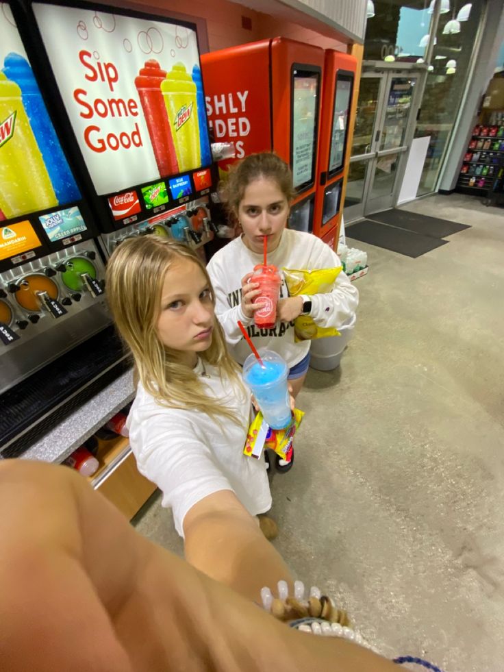 two girls in a store looking at something on the floor and one girl is holding a toy