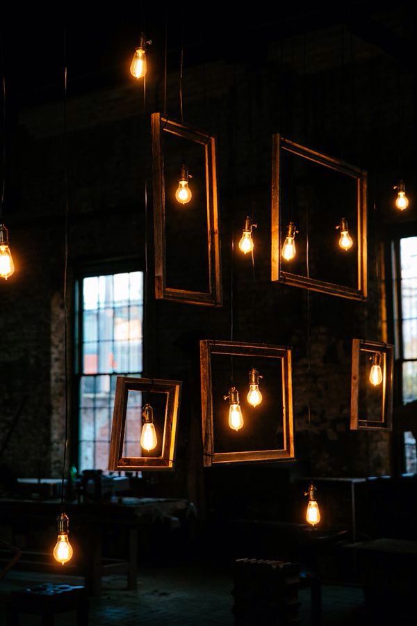 some light bulbs hanging from the ceiling in a dark room with windows and framed pictures