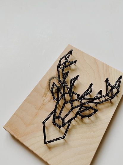 a sculpture made out of black wire sitting on top of a wooden board