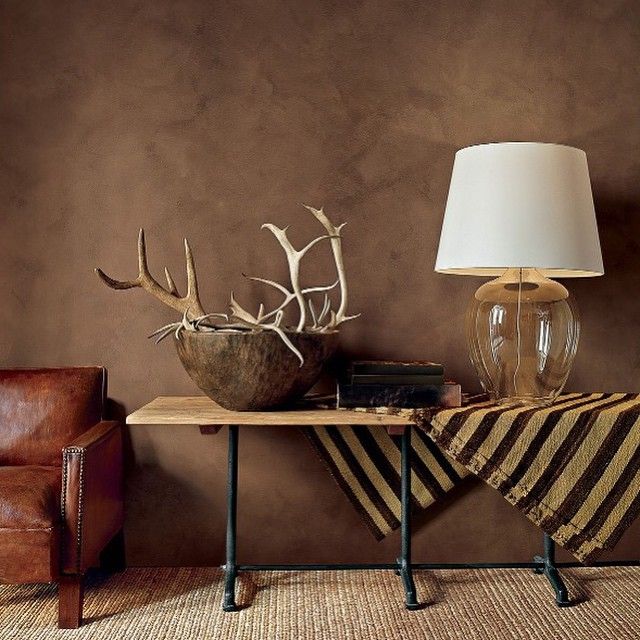 two antlers are sitting on a table next to a lamp and a leather chair