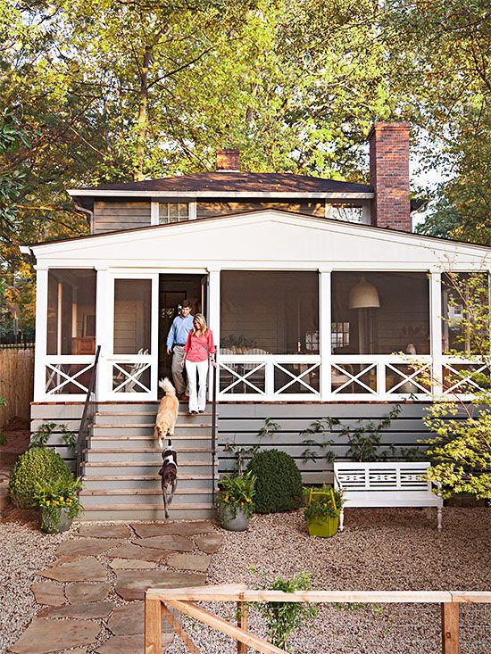 two people standing on the porch of a small house with stairs leading up to it