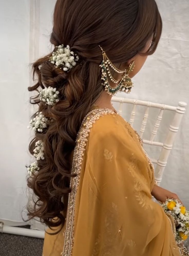 a woman with long hair and flowers in her hair, wearing a yellow sari