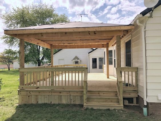 a covered porch with stairs leading up to the front door and back deck area on a sunny day