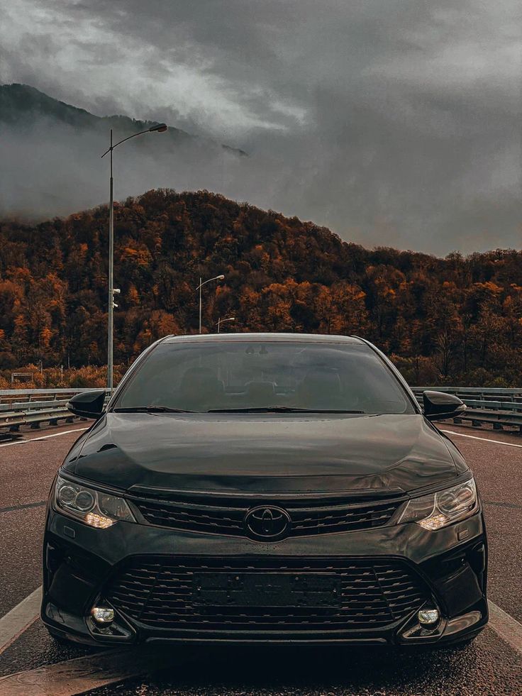 a black car parked on the side of a road in front of a mountain range