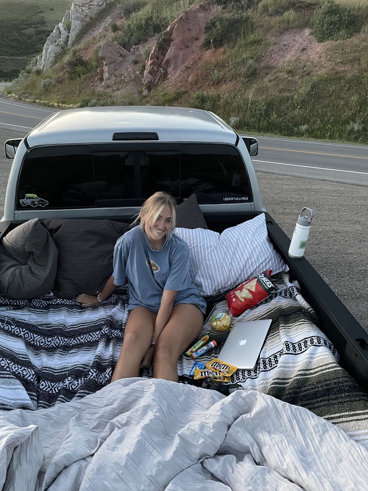 a woman sitting in the back of a pick up truck on top of a bed