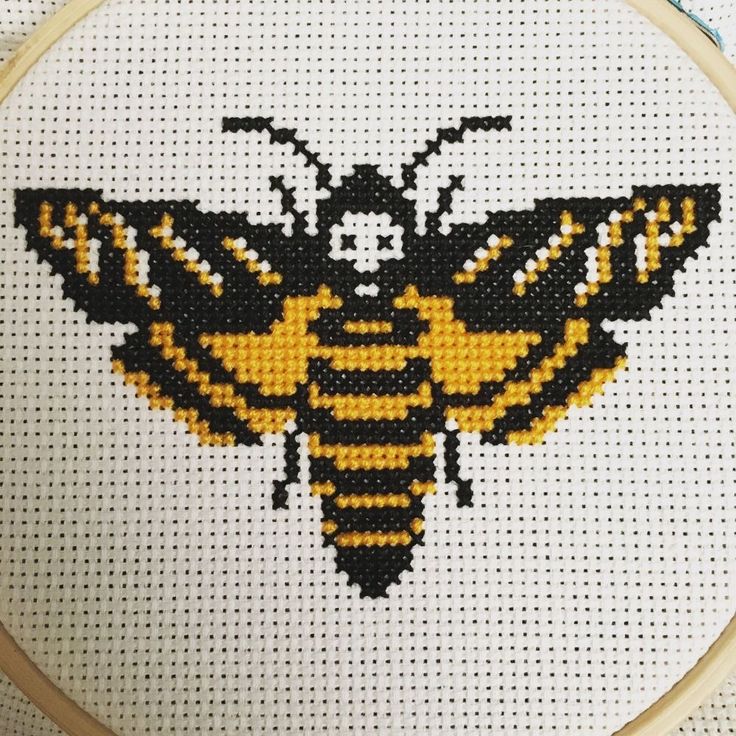 a cross - stitch bee with yellow and black wings on it's back side