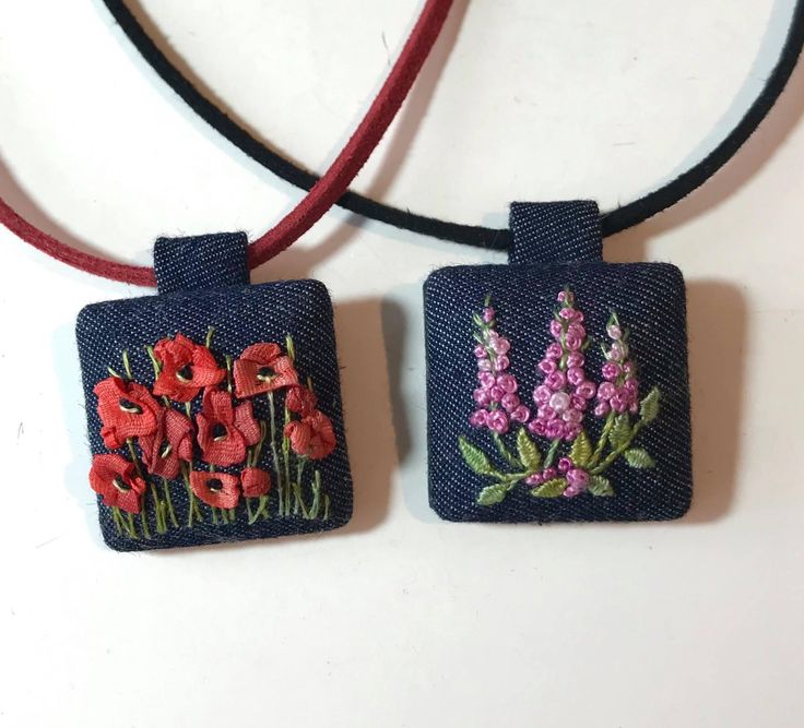 two square pendants with flowers on them sitting on a table next to each other