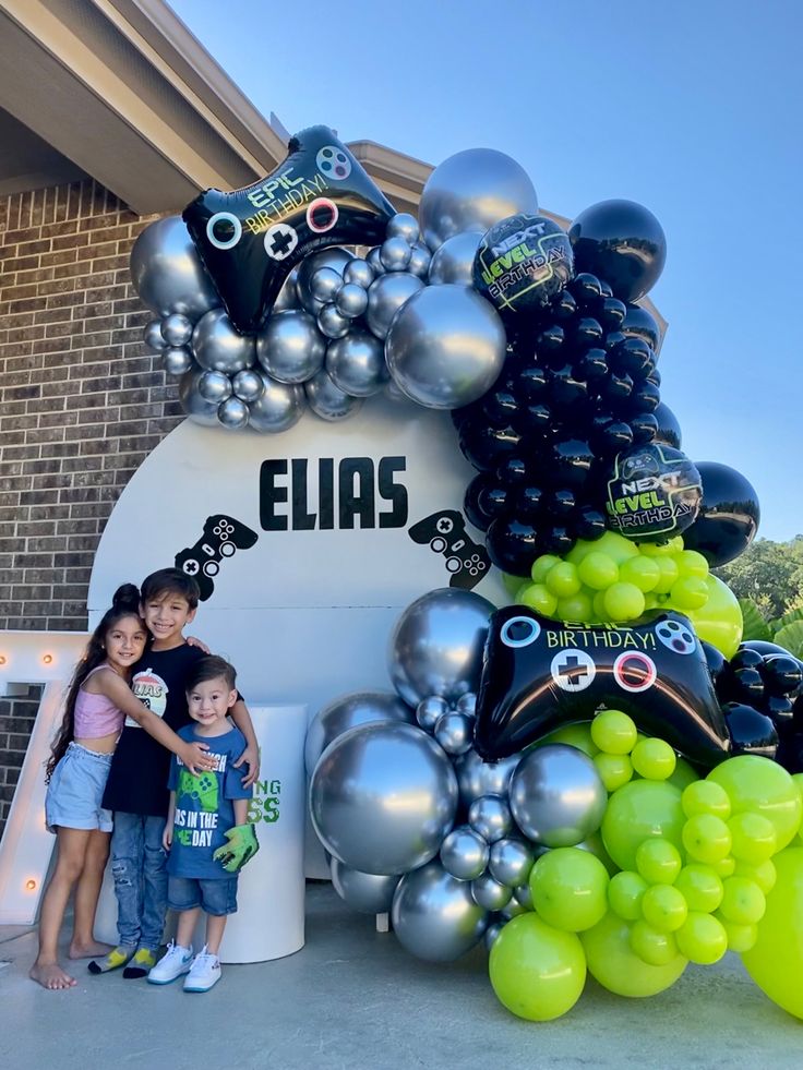 two children standing in front of a bunch of balloons