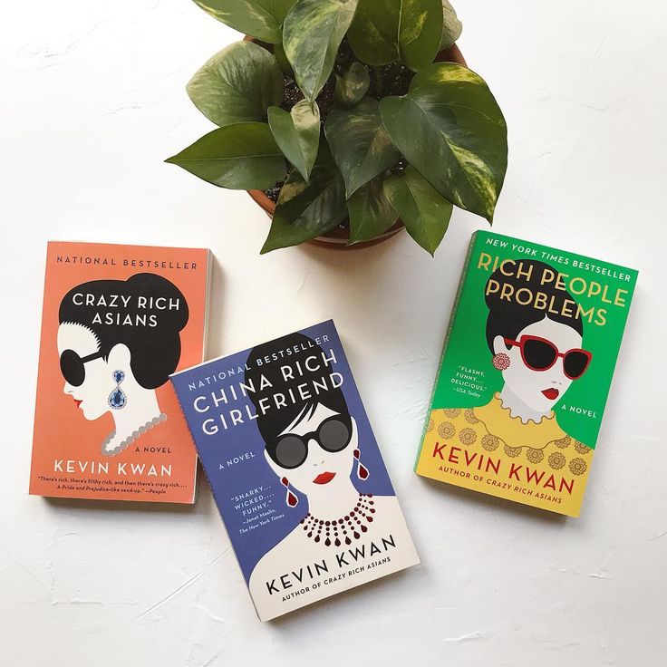 three books sitting on top of a white table next to a potted plant with green leaves