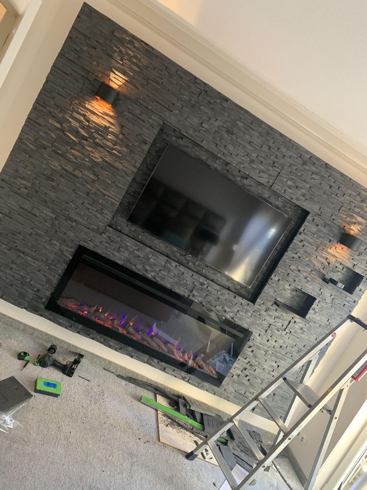 a living room with a fire place next to a tv mounted on a brick wall