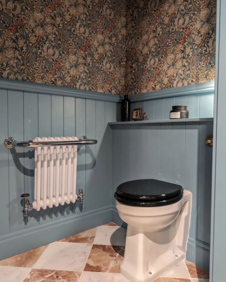 a toilet in a bathroom with blue walls and floral wallpaper on the walls, along with a radiator