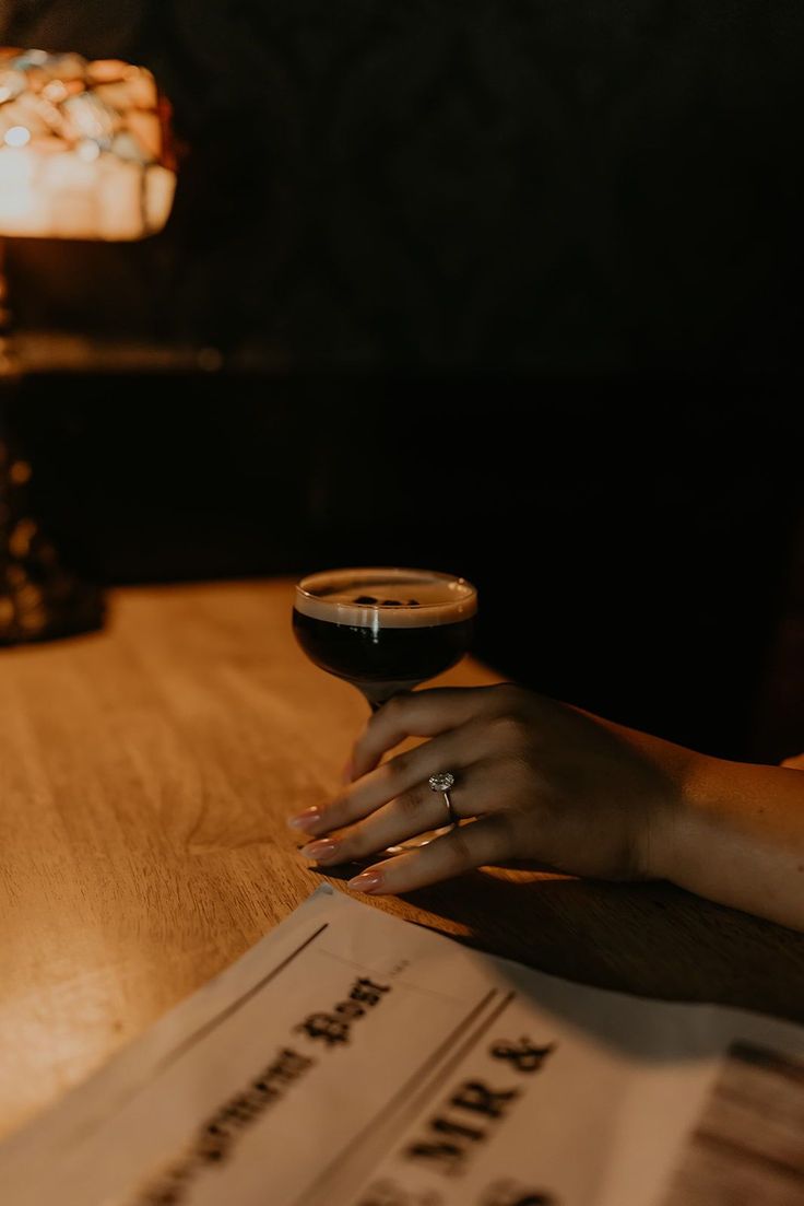 a person sitting at a table with a glass of wine in front of them and newspaper on the table